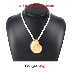 Collier avec pendentif coquillage doré et cordon tressé blanc sur un support à bijoux