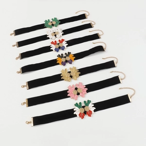 Close-up of velvet chokers with colorful enamel flowers and adjustable gold chains