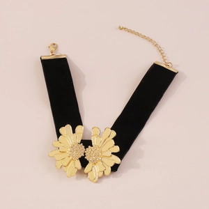 Detail of black velvet choker featuring symmetrical golden flowers and adjustable clasp