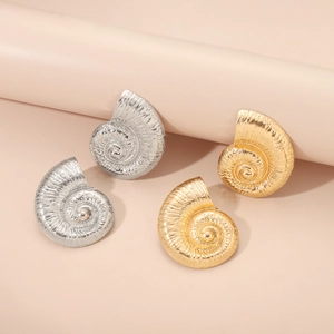 Détails macro des boucles d'oreilles en forme de conque en métal or et argent poli