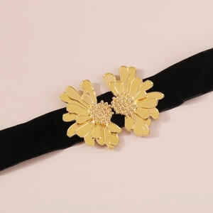 Detail of golden metal floral petals with dotted texture on black velvet neck strap