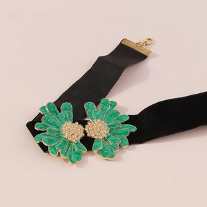 Detailed close-up of velvet choker featuring gold-edged green enamel flower pendants