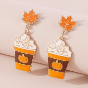 Detailopname van de emaille pompoen koffiekop en esdoornblad oorbellen voor Halloween