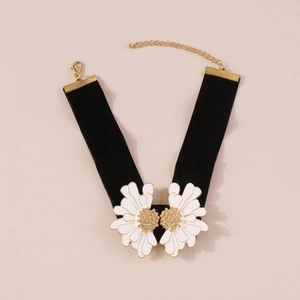 Macro detail of black velvet choker featuring white daisy charms and golden clasp