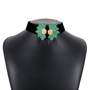 Detail of black velvet choker featuring symmetrical green enamel flowers and gold centers