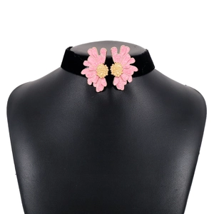 Close-up of black velvet choker featuring symmetrical pink flower charms and golden details