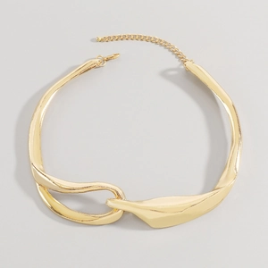 Dettaglio della collana in metallo dorato con design scultoreo e chiusura a moschettone