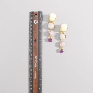 Pendientes largos con piedras de resina de colores junto a una regla para medir el tamaño