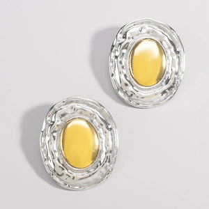 Detailed close-up of mixed metal oval earrings featuring hammered silver and gold finish