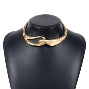 Dettaglio della collana a maglie dorate intrecciate indossata su un busto nero opaco