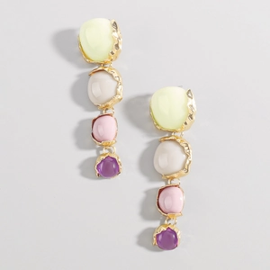 Detalle de pendientes largos con piedras de resina coloridas y engastes dorados texturizados