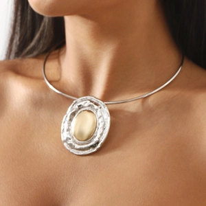 Detail of two-tone oval pendant with silver hammered texture and gold mirror center