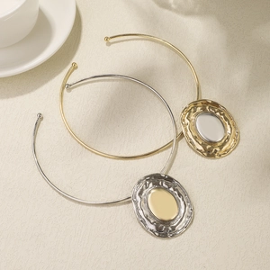 Detailed macro view of gold and silver tone metal chokers with oval hammered pendants