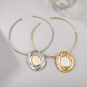 Detail of minimalist mixed metal oval necklaces with hammer textured pendants and two-tone finish