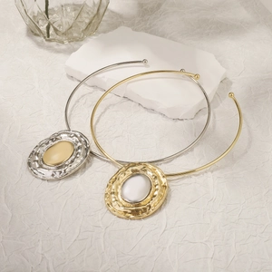 Detail of minimalist torque necklaces featuring two-tone metal finishes and wave texture