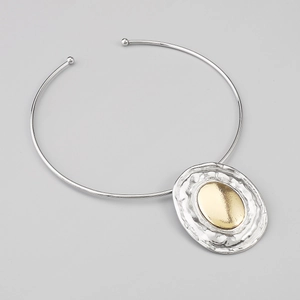 Macro detail of mixed-metal oval pendant with gold insert and hammered silver texture