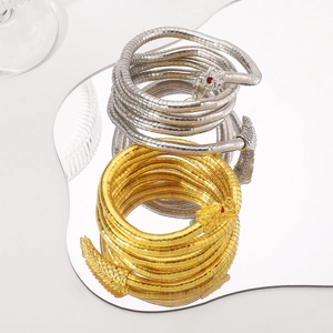 Nahaufnahme der goldenen und silbernen Schlangenarmbänder mit roten Edelsteinaugen auf Spiegelglas