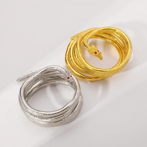 Detailansicht von silbernen und goldenen Drachenarmbändern mit roten Edelsteinaugen