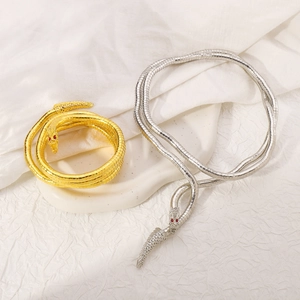 Details einer Schlangenkette mit Schuppenstruktur und roten Edelsteinaugen in Gold und Silber