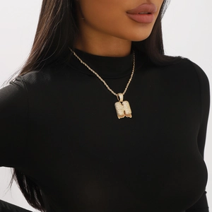 Macro shot of gold twist chain with sparkling zircon-encrusted letter H bubble pendant