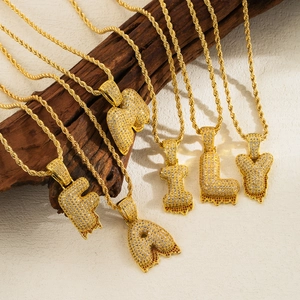 Detailed shot of golden bubble letters FAMILY necklaces with crystals on wood