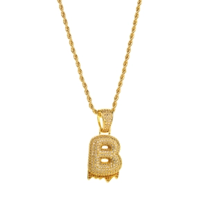Close-up of golden letter B pendant with white zircon pavé and yellow melting droplets