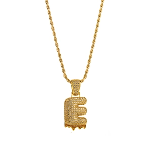 Macro shot of gold letter E pendant with white zircons and red lava drip detail