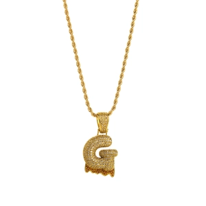 Detail of hip hop gold necklace with large iced-out letter G pendant and lava drip effect