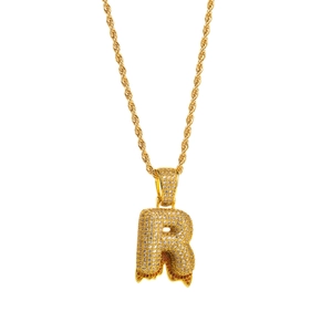 Close-up of hip hop letter R pendant with white zircon stones and orange drip detail