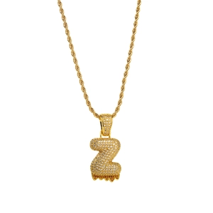 Macro detail of iced-out Z letter pendant with orange lava drip on golden rope chain