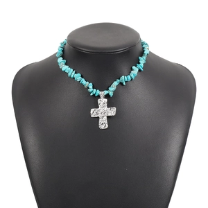 Dettaglio collana in scaglie di turchese con croce d'argento testurizzata su busto nero