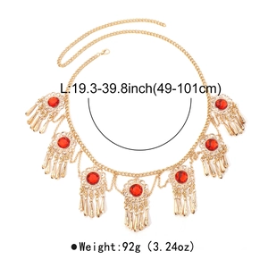 Detail of vintage gold metal waist chain with red zircon charms and ethnic tassels