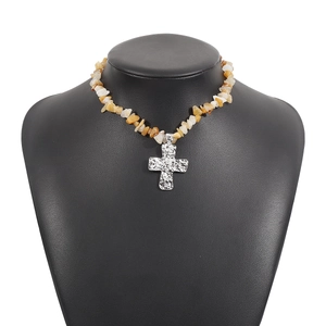 Dettaglio macro del ciondolo a croce martellata su collana di pietre naturali grezze