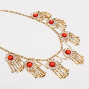 Detailed macro view of vintage gold tassel waist chain with red zircon stones