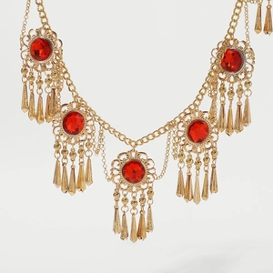 Close-up of golden tassel waist chain with large red faceted gemstones in bohemian style