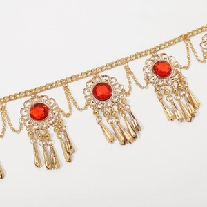 Detailed close-up of Bohemian gold metal waist chain with red stones and tassels