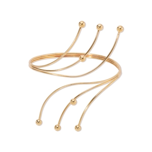 Detailed view of multilayer gold coiled arm cuff with metallic bead accents on a white base
