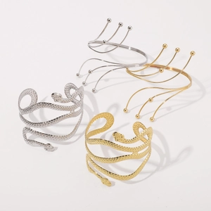 Exaggerated snake arm cuff and layered metal open arm bracelet in gold and silver