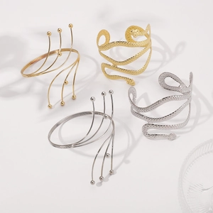 Detail of snake arm cuffs and beaded swirl bangles in polished gold and silver finish