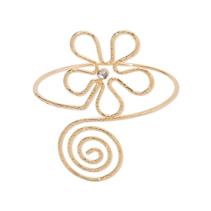 Detailed macro of golden adjustable arm cuff featuring flower motif and hammer textured metal
