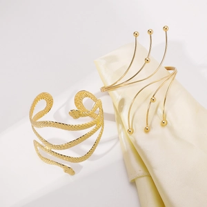 Detailed view of gold snake arm cuff and multi-layer beaded ring on silk fabric