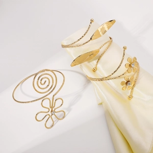 Detail of adjustable gold arm cuffs featuring spiral patterns and polished flower leaves