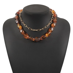 Detail der bernsteinfarbenen Harzperlen und goldenen Kette am geschichteten Choker