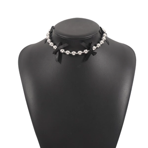 Gothic style silver beaded choker with black ribbon bows on a mannequin display