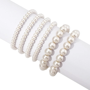 Set of six handmade pearl bracelets with four thin and two thick strands on a white stand