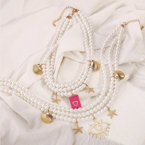 Détail d'un collier de perles multicouche avec coquillages dorés, étoiles de mer et breloques