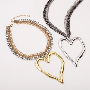 Détail de colliers punk multicouches avec pendentifs cœur et chaînes cubaines bicolores