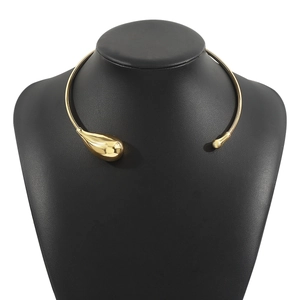 Detailaufnahme eines glänzenden goldenen asymmetrischen Chokers mit Tropfen- und Kugeldesign