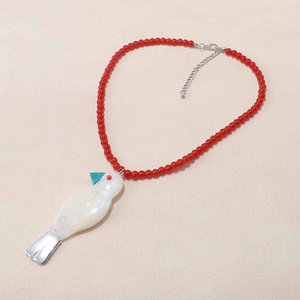 Dettaglio della collana di perline rosse con ciondolo a uccellino in resina e chiusura argento
