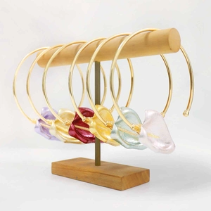 Detailaufnahme metallischer Calla-Lilien-Anhänger an goldenen Halsreifen in bunten Farben